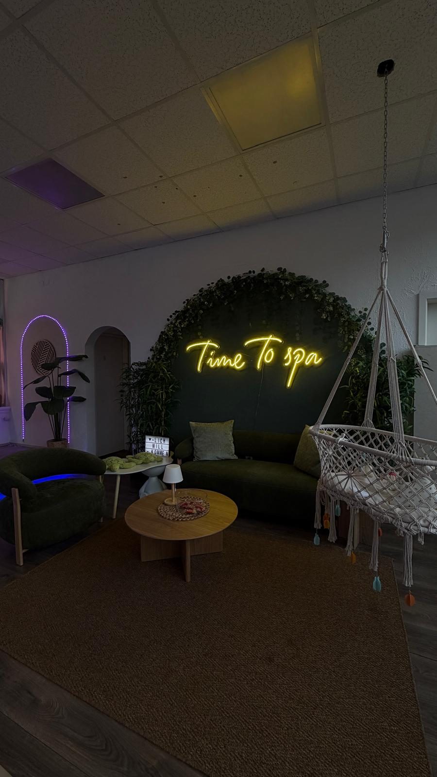 Sitzbereich mit Samtsofa, Hängewiege und Neonschriftzug Time To spa
